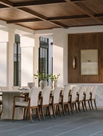 A sunlit dining room with a timber ceiling and long table