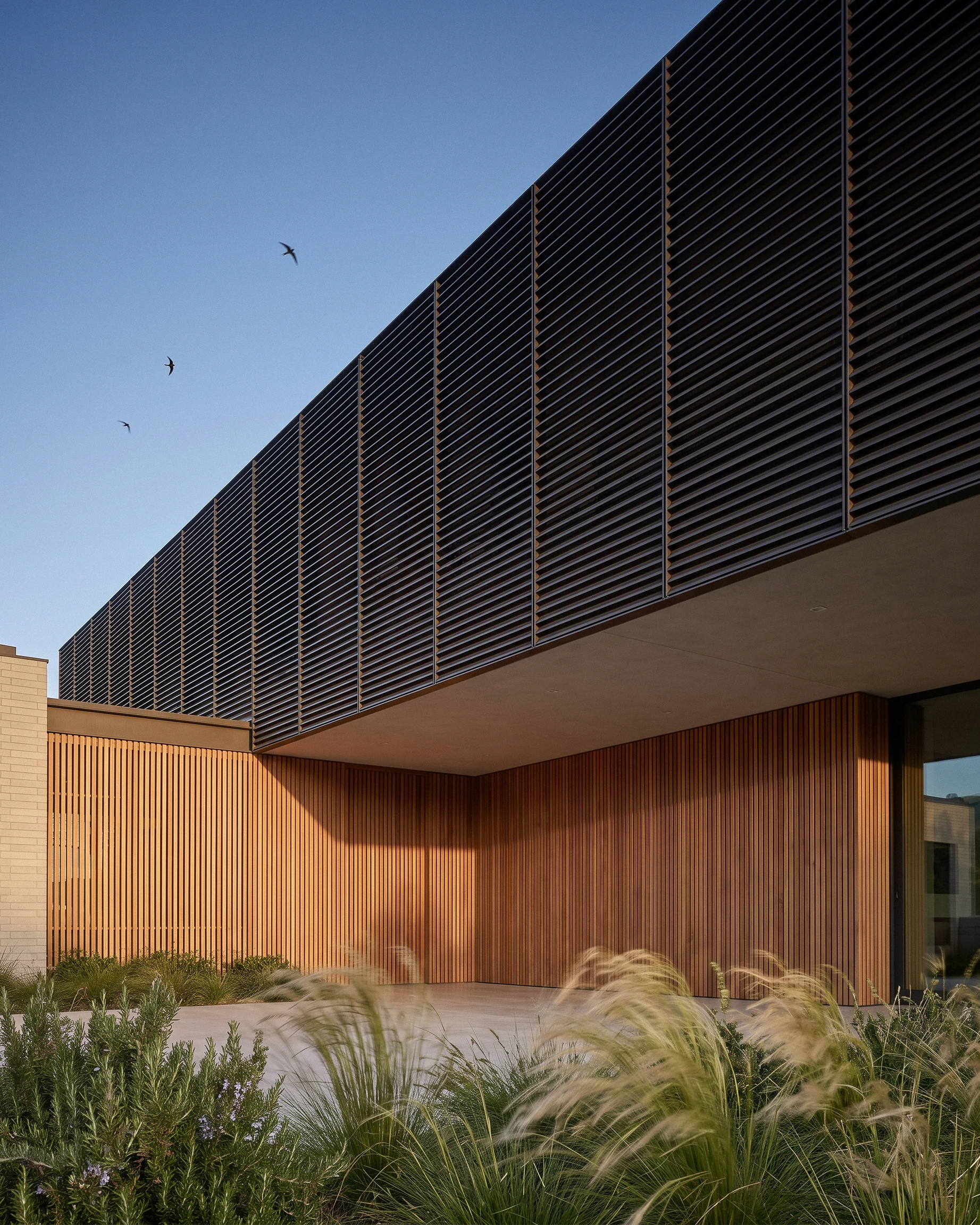 Dark horizontal screens above timber cladding and garden planting at Tiffany Ranch.